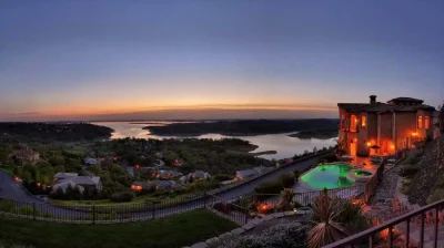 A stunning panoramic view of a luxury home and pool at dusk, overlooking Folsom Lake in El Dorado Hills. The image highlights Horizon Fence & Custom Gates' expertise in installing high-end custom fences and gates for prestigious properties.
